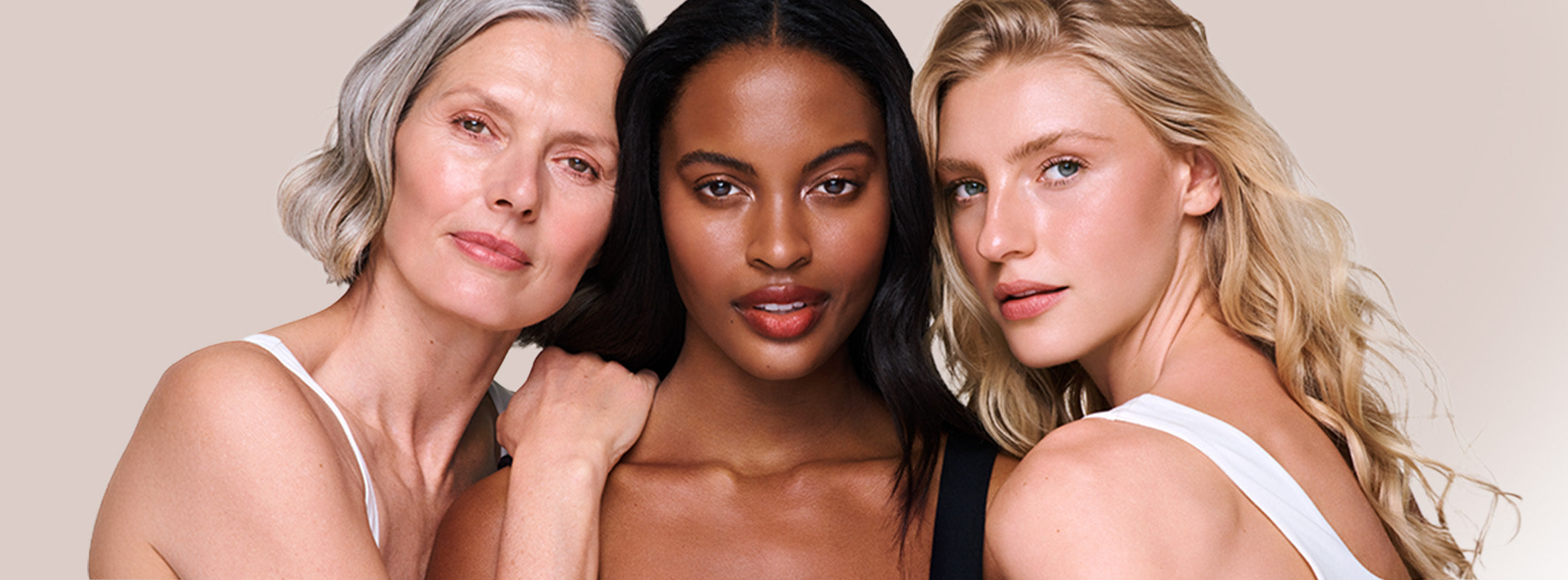 Three diverse individuals with glowing skin stand close together against a neutral beige background.