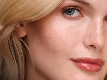A close-up shot of a person with fair, freckled skin, blonde hair, and blue eyes.. 