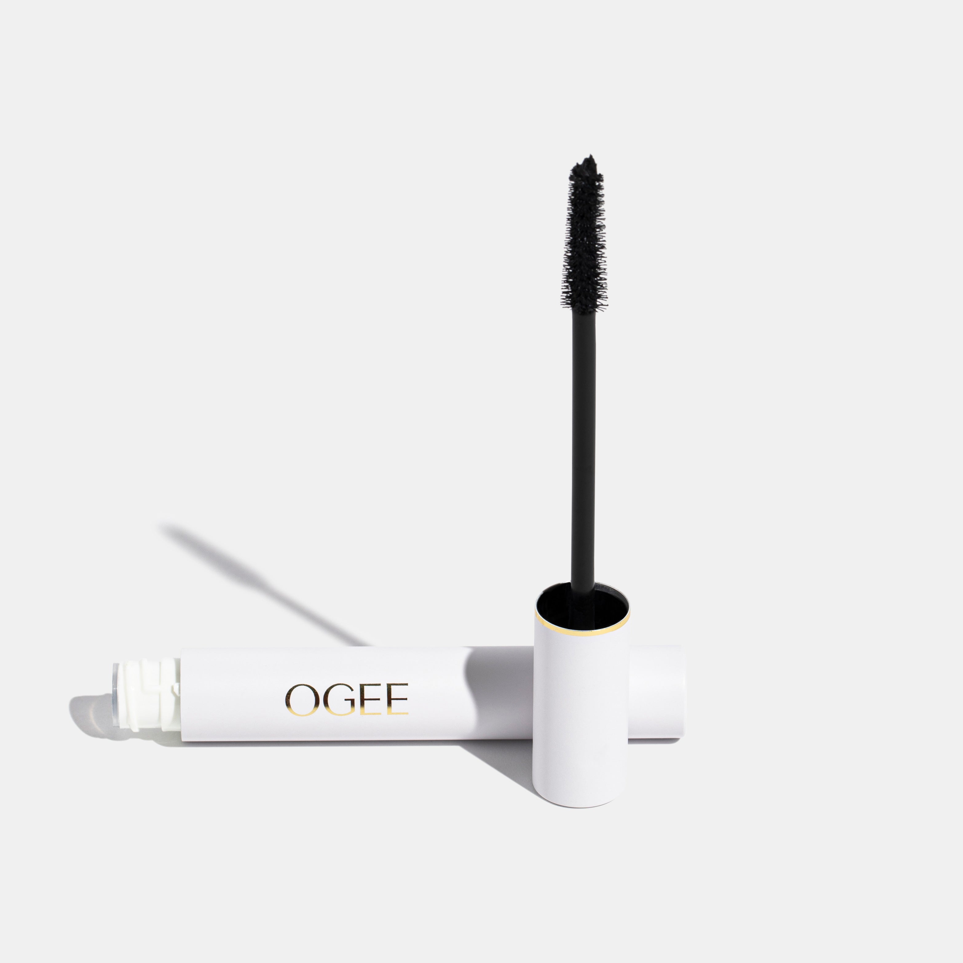 An image of Ogee's mascara, with the wand standing up and the tube lying on its side.